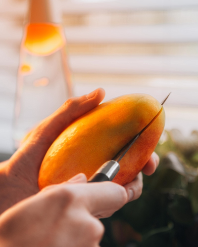 Close-up of hands slicing a ripe mango to make homemade mango sorbet for expecting moms.